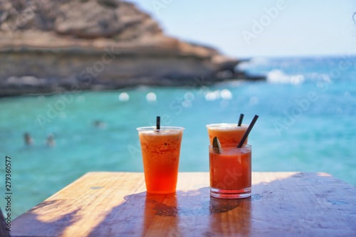 Gemütlich Coktails trinken in einer Bar vor tropischer Bucht mit klarem türkisem Wasser bei Sonnenschein und blauen Himmel