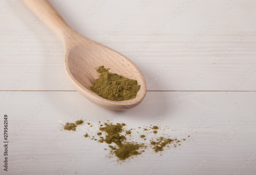 Moringi powder in a wooden spoon on a white wooden background. horizontal. Moringi powder in a wooden spoon on a white wooden background. horizontal.