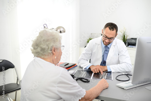 handsome doctor giving medical consultation diagnostic to elderly senior woman in hospital office