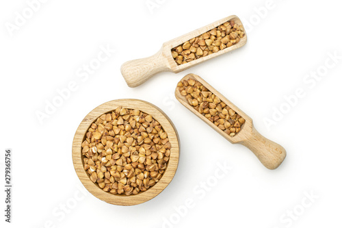 Lot of whole hulled raw brown buckwheat grain in a wooden bowl with wooden scoop flatlay isolated on white background