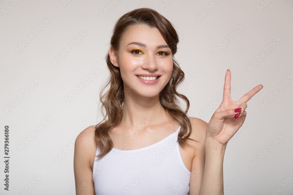 Young smiling woman showing gesture over light background. Two fingers up Young smiling woman showing gesture over light background. Two fingers up