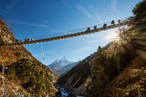 Fototapeta Naklejka Na Ścianę i Meble -  Trekkers on rope hanging suspension bridge on the way to Mount Everest base camp near Namche Bazar - Nepal