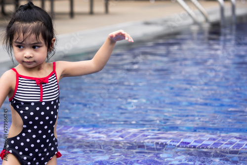 Fototapeta Naklejka Na Ścianę i Meble -  Cute female asian child while on a swimming pool during hot summer. Closeup shot of asian child on swimsuit