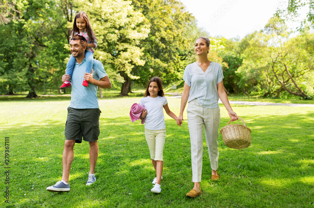 Fototapeta premium family, leisure and people concept - happy mother with picnic basket, father and two daughters walking in summer park