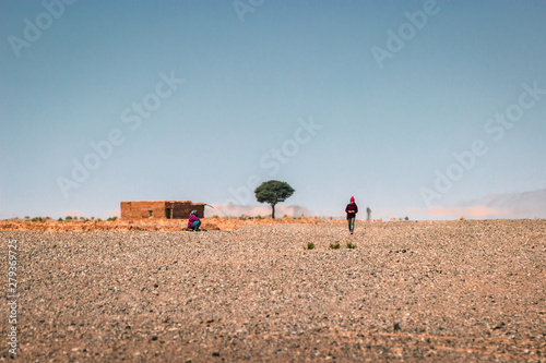 A women, tree and mud house in the Sahara desert. Reportage in Africa