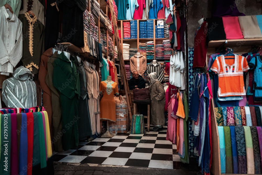 Men discussing in a shop for clothes and fabrics in the center of Marrakech, Morocco