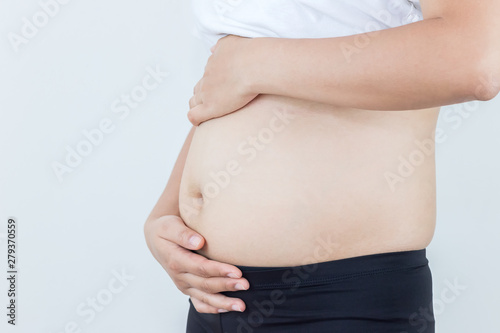 Happy pregnant woman holds hands on belly on a white background. Concept of first weeks pregnancy. © sek1111