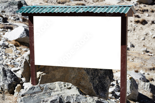 Information board made of wood, in the background a rocky mountain slope.