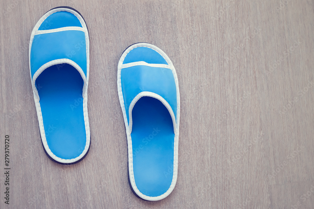 Blue house slipper on wooden background. Soft comfortable home slipper. Blue house slipper on wooden background. Soft comfortable home slipper.
