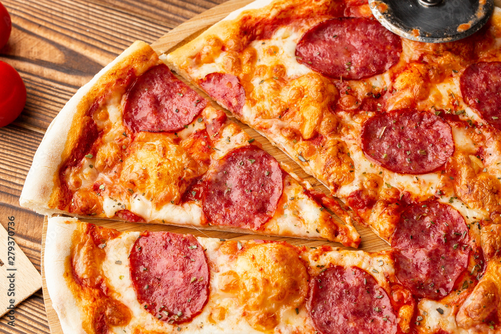 Delicious hot homemade Pepperoni pizza on the wooden table. Pepperoni Pizza - Fresh homemade pizza with pepperoni, cheese and tomato sauce on rustic black stone background with copy space. Delicious hot homemade Pepperoni pizza on the wooden table. Pepperoni Pizza - Fresh homemade pizza with pepperoni, cheese and tomato sauce on rustic black stone background with copy space.