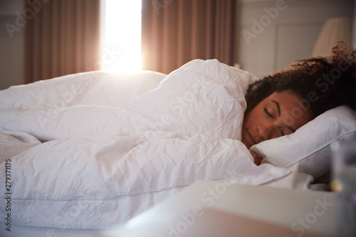 Peaceful Woman Asleep In Bed As Day Break Through Curtains photo