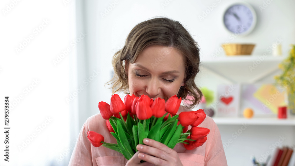 Beautiful woman sniffing red tulips, present from boyfriend, holiday celebration Beautiful woman sniffing red tulips, present from boyfriend, holiday celebration