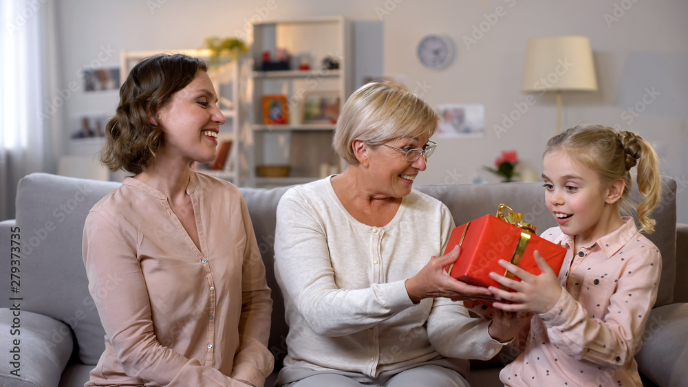 Grandmother and daughter giving present to schoolgirl, motherhood care, love Grandmother and daughter giving present to schoolgirl, motherhood care, love