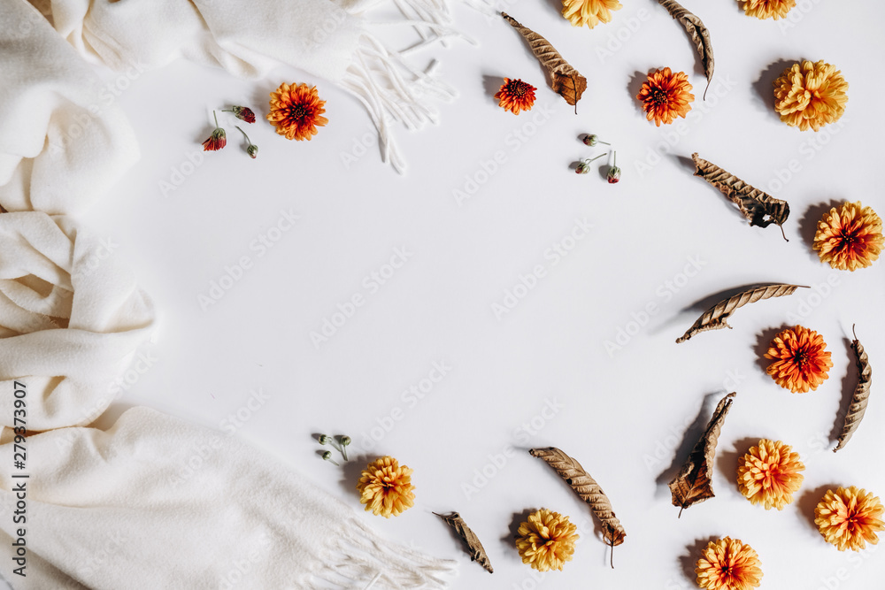 Autumn composition. Orange flowers, scarf and dried leaves on gray background. Flat lay, top view, copy space