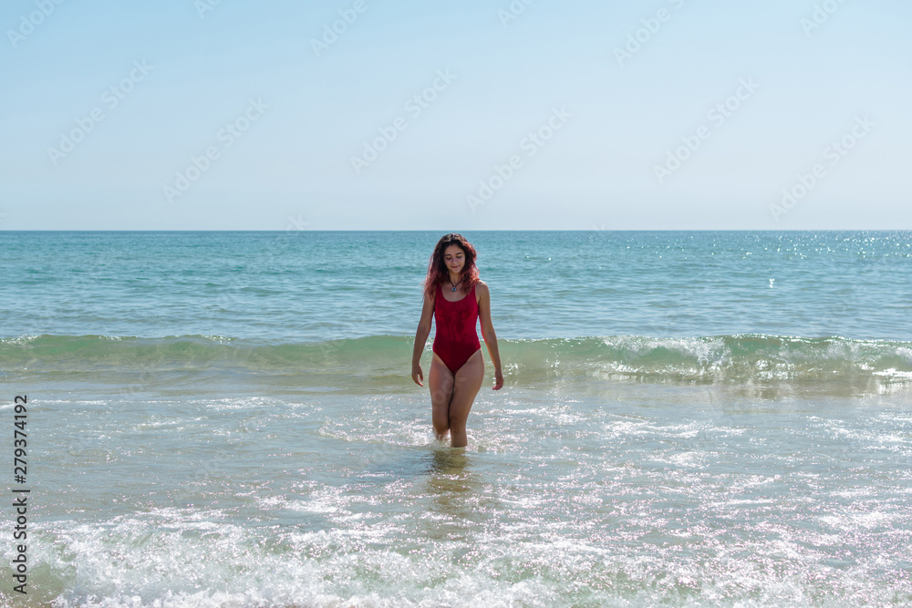 Young woman walking through the sea and having a good time