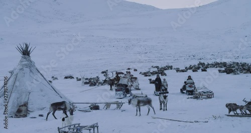 People living in yurts In Arctic in the middle of field, people wearing a traditional fur , reindeers are beside them , typical day on the tundra photo