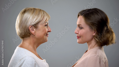 Aging process, adult mum and daughter looking at each other, future reflection