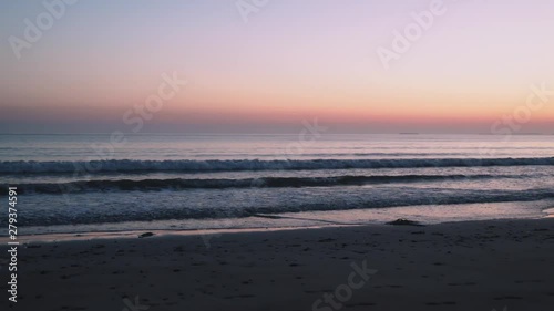 Beautiful sunset at the beach, sea waves break on sand beach. photo