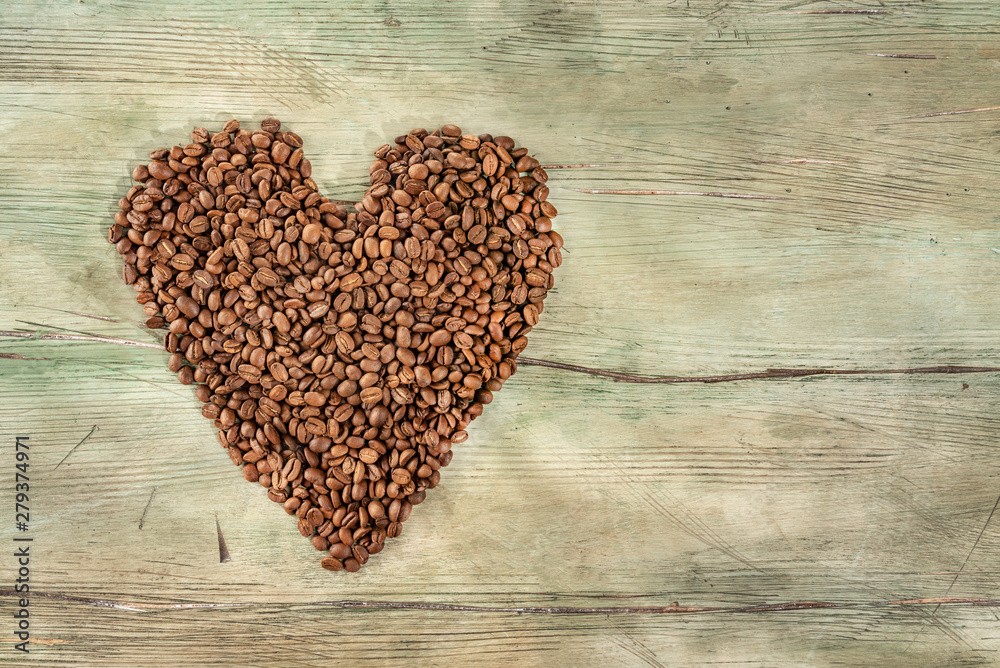 Coffee beans heart on wood weathered background. Bean creation of a loving heart