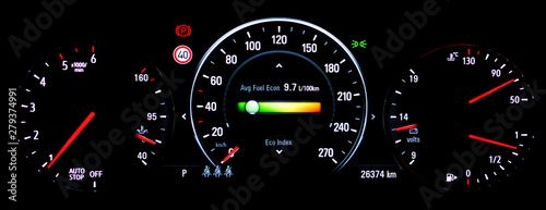 Modern illuminated car instrument panel with speedometer, tachometer, odometer, car's temperature gauge and car voltmeter gauge. Average fuel economy consumption display on car dashboard panel.