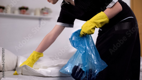 Quadro su tela Chambermaid gathering trash from bed in morning after party, cleaning service