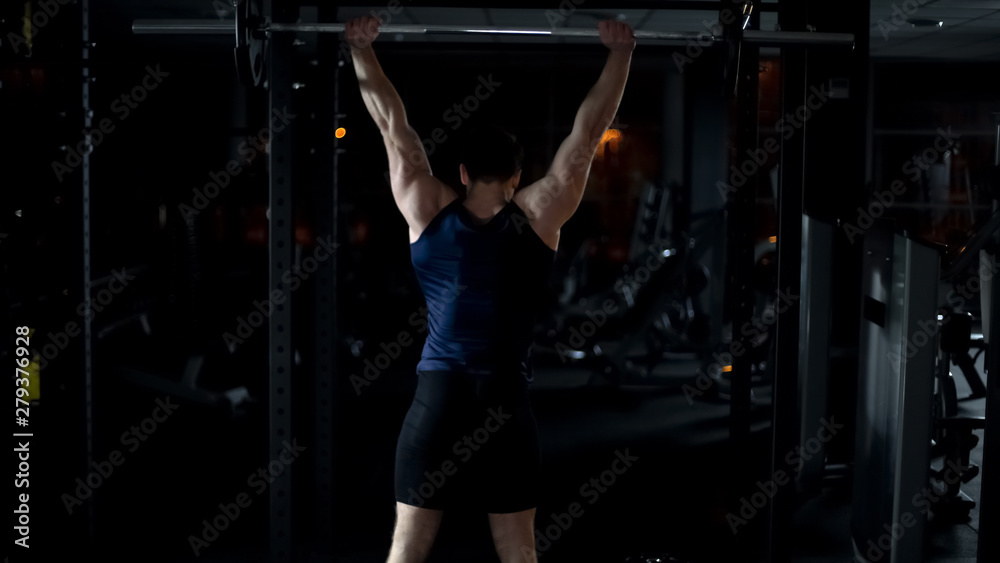 Fototapeta premium Powerlifter doing exercise with barbell, training arms and shoulders muscles