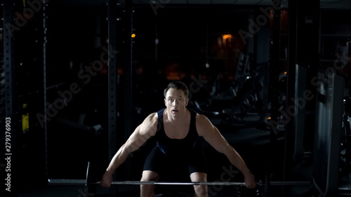 Strong bodybuilder easily raises up heavy barbell, training workout program