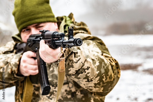 A soldier with a gun AKM, aims at the enemy. Barrel and muzzle machine close up.