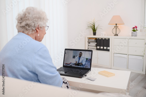 elderly senior woman, having a remote medical consultation with her doctor over internet computer telemedecine diagnostic photo