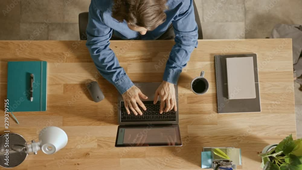 Top View Zoom Out Shot: In the Office Businessman Sitting at the Wooden Desk Opens Laptop and Starts Working He Drinks Coffee, Types, Writes Emails, Surfs the Internet, Designs Software