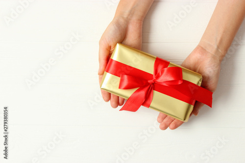 gift in female hands on a colored background top view.