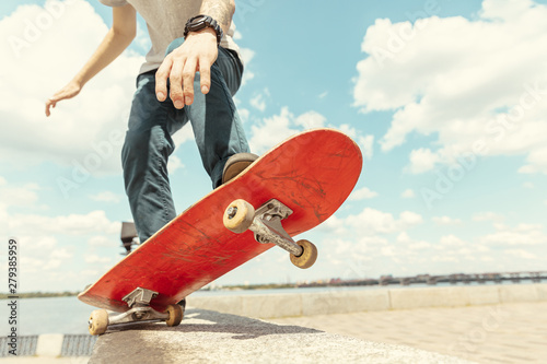 Skateboarder doing a trick at the city's street in sunny day. Young man in sneakers and cap riding and longboarding on the asphalt. Concept of leisure activity, sport, extreme, hobby and motion.