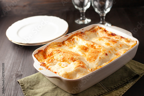 Lasagna in a white pan stabding on a green towel