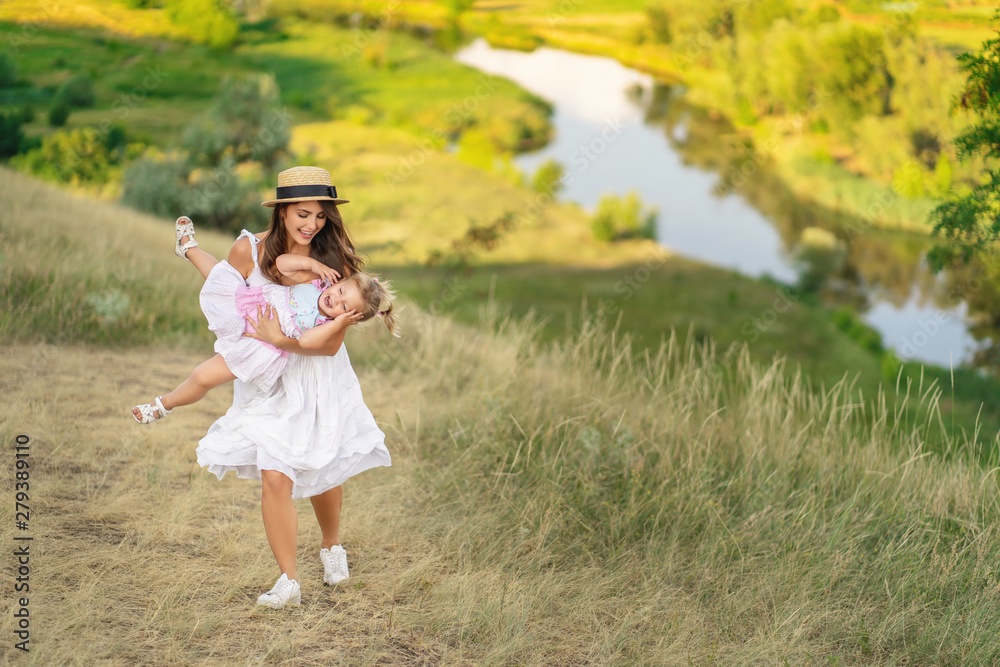 Stilish mother and daughter having fun on the nature. Mothers day.