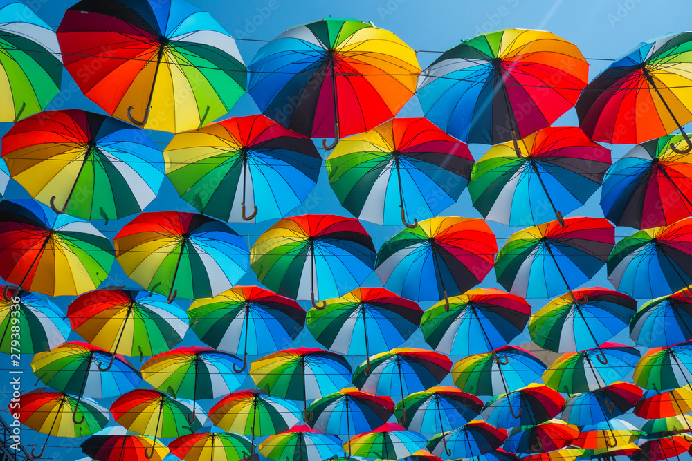 outdoors decoration with many colorful umbrellas against blue sky and sun	