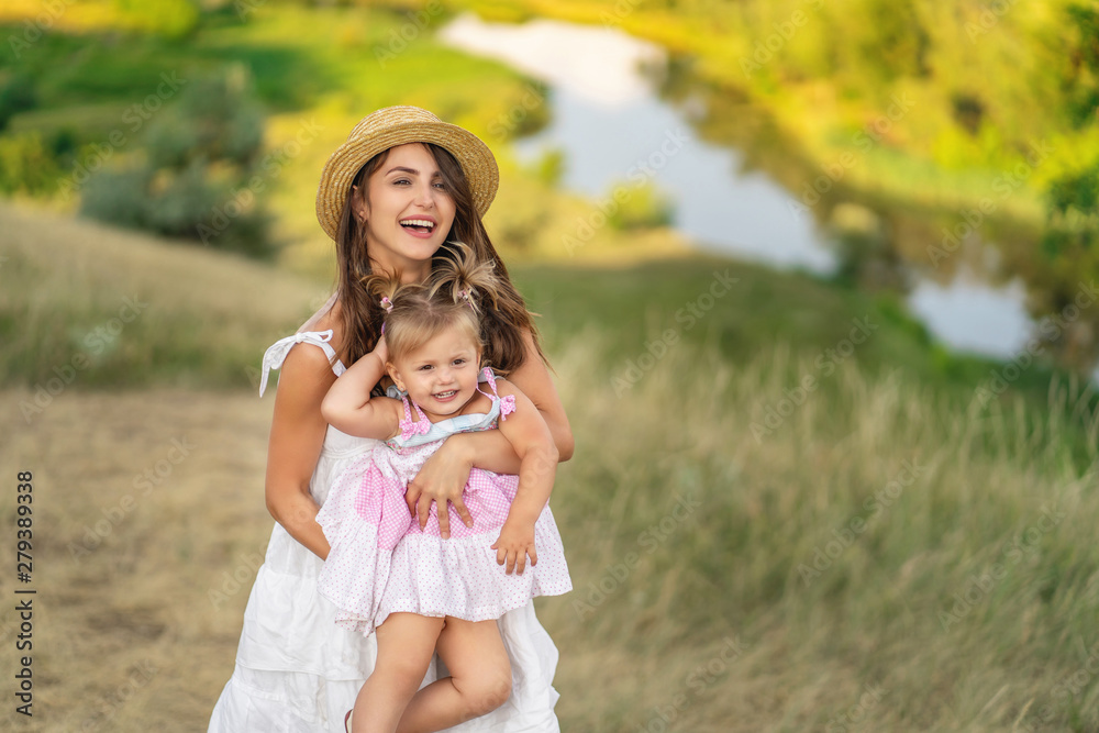 young mother and daughter walking through a rural area with a beautiful landscape young mother and daughter walking through a rural area with a beautiful landscape