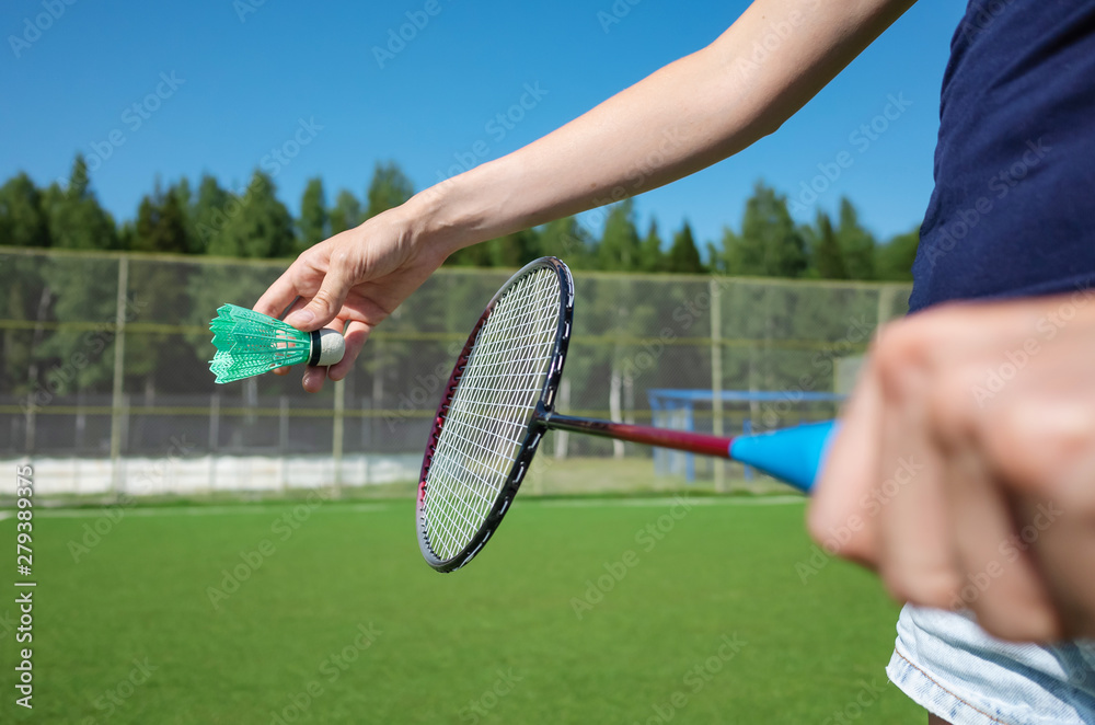 Woman with a badminton racket. Ahead is the stadium. The concept of summer hobbies, activity, amateur badminton, sports.