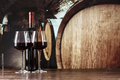 Fotografie, Tablou red wine in a glass on the background of barrels in the cellar