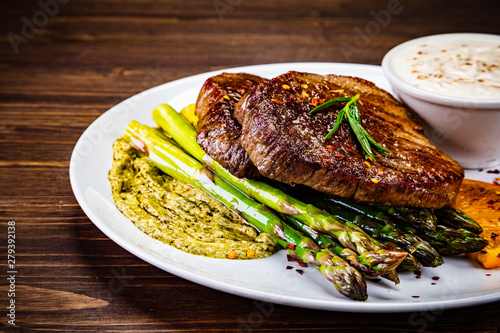 Grilled steak with asparagus on wooden background