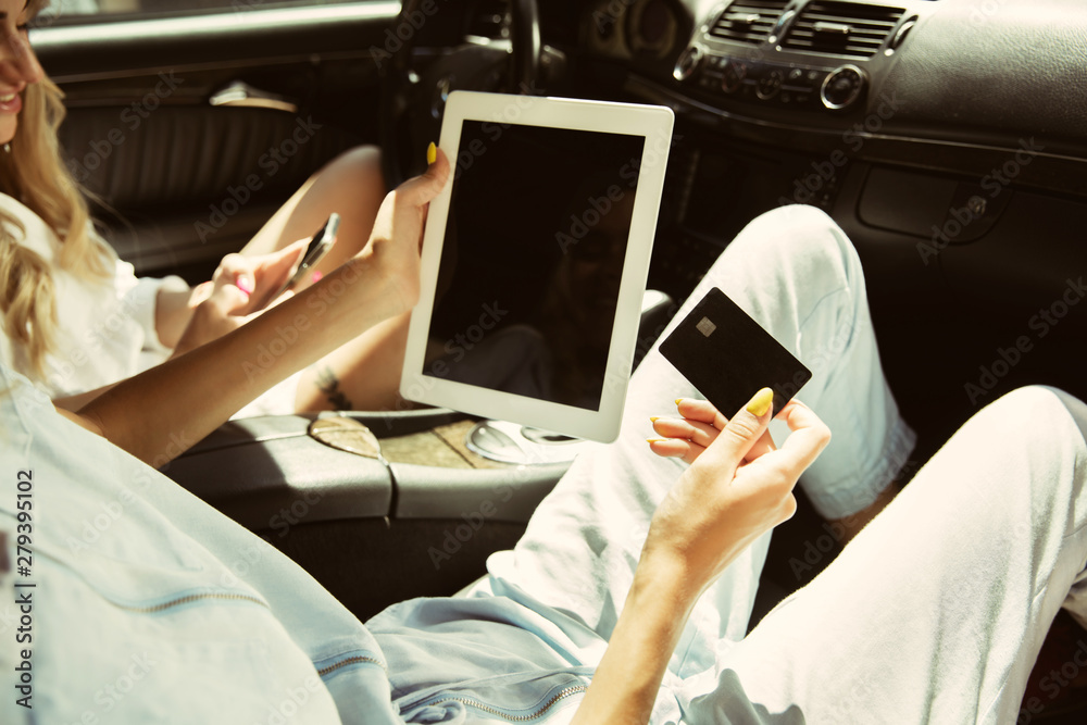 Young lesbian's couple preparing for vacation trip on the car in sunny day. Women sitting and ready for going to sea, riverside or ocean. Concept of relationship, love, summer, weekend, honeymoon.