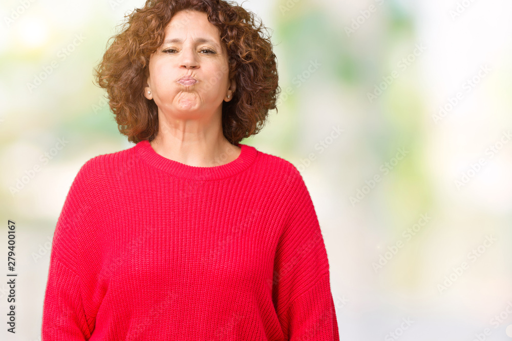 Beautiful middle ager senior woman red winter sweater over isolated background puffing cheeks with funny face. Mouth inflated with air, crazy expression. Beautiful middle ager senior woman red winter sweater over isolated background puffing cheeks with funny face. Mouth inflated with air, crazy expression.