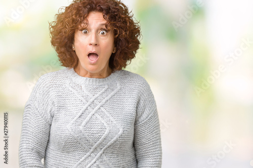 Beautiful middle ager senior woman wearing winter sweater over isolated background afraid and shocked with surprise expression, fear and excited face. © Krakenimages.com