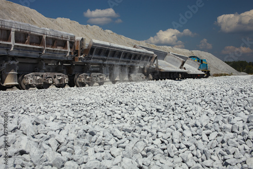 Railway dump-car after unloading gravel in quarry for limestone mining. Mining industry. Quarry and mining equipment.