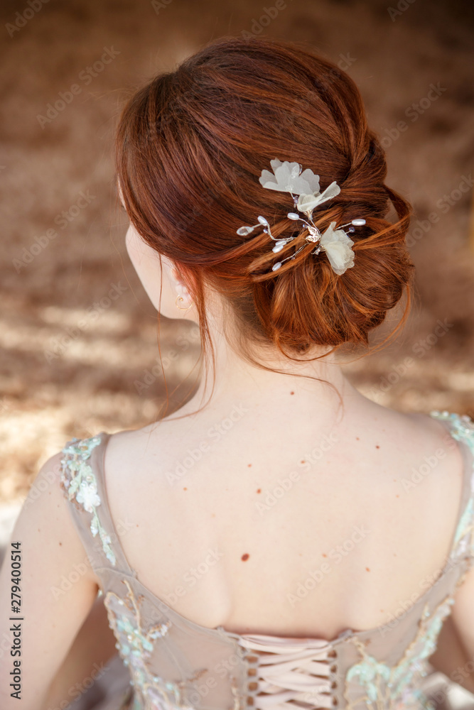 Sweet red-haired bride with an elegant hairstyle view from the back.