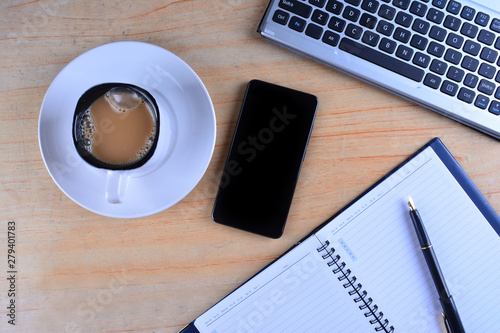 Cup of Coffee with keyboard and mouse, fountain pen, notebook, calculator and smartphone on a table