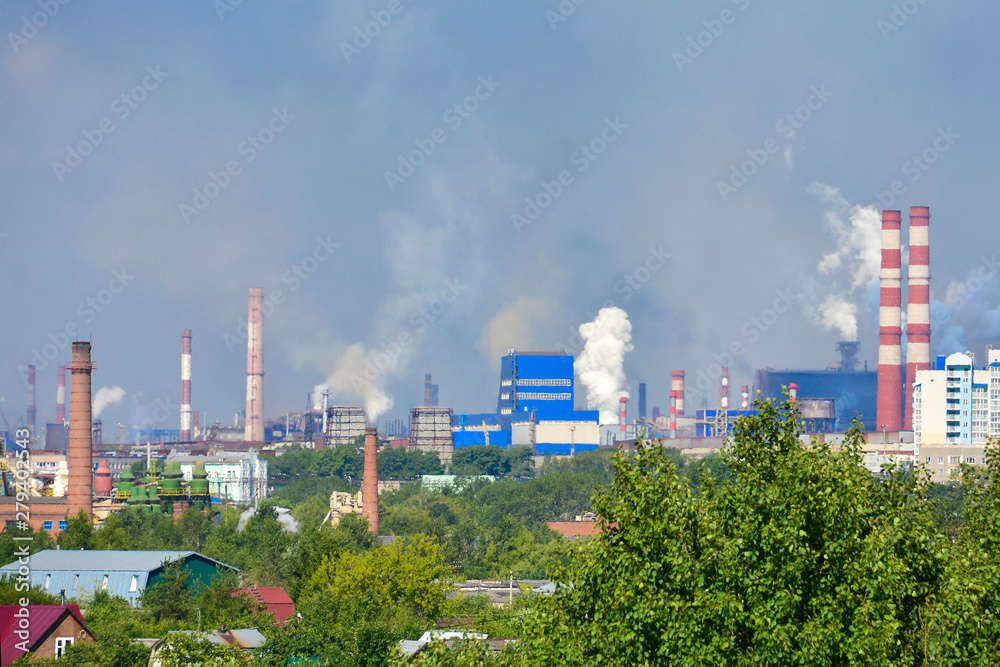Heavy smoke industrial chimneys causing air pollution problems. Emissions are visible over residential areas of the city. Environmental pollution. Factory pipe, polluting the air.