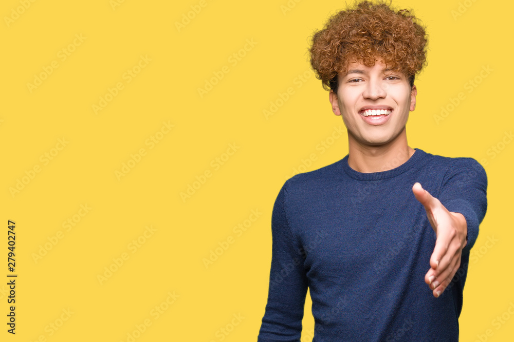 Young handsome man with afro hair smiling friendly offering handshake as greeting and welcoming. Successful business. Young handsome man with afro hair smiling friendly offering handshake as greeting and welcoming. Successful business.