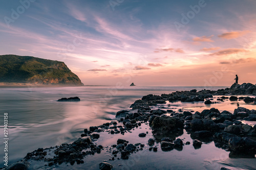 Long exposure sunset at Karekare with a fisherman