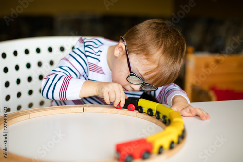 little ginger boy with glasses with syndrome dawn playing photo