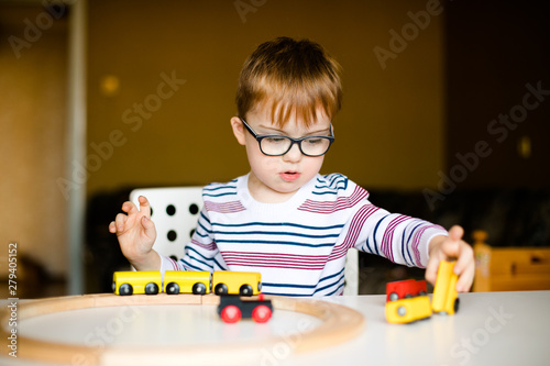 little ginger boy with glasses with syndrome dawn playing photo